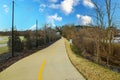 A shot of a smooth concrete bike path with a yellow line in the middle with lush green and autumn colored trees and grass Royalty Free Stock Photo