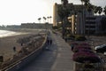 A shot of a smooth winding bike trail at the beach at sunset with people riding and walking on the trail surrounded by palm trees Royalty Free Stock Photo