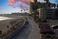 A shot of a smooth winding bike trail at the beach at sunset with people riding and walking on the trail surrounded by palm trees Royalty Free Stock Photo