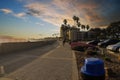 A shot of a smooth winding bike trail at the beach at sunset with people riding and walking on the trail surrounded by palm trees Royalty Free Stock Photo