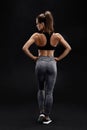 Shot of a strong woman with muscular abdomen in sportswear. Fitness female model posing on black background. Royalty Free Stock Photo