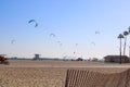 A shot of a sunny day at the beach with people flying kites and blue sky