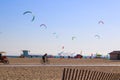 A shot of a sunny day at the beach with people flying kites and blue sky