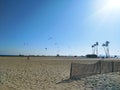 A shot of a sunny day at the beach with people flying kites and blue sky