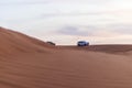 Shot of a SUV vehicle driving trough sand dunes. Desert