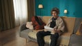 Shot of a teenager, young man sitting on a sofa, couch, reading a document, paper, admission, waiting to see positive Royalty Free Stock Photo