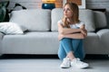 Thoughtful young woman looking to the side while sitting on the floor in the living room at home Royalty Free Stock Photo