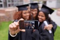 Memories of monumental moments. Shot of three female graduates taking a picture of themselves on a phone. Royalty Free Stock Photo