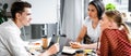 Shot of three multiethnic friends sitting at table and talking in apartment Royalty Free Stock Photo