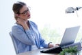 Tired young woman with neck pain using her laptop at home.