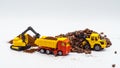 A toy excavator loads coffee beans into the back of a toy truck with a bucket, and a toy bulldozer rakes roasted coffee beans into Royalty Free Stock Photo