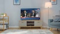 Shot of a TV with Live News Channel. Cozy Living Room at Day Time with a Chair and Lamps Turned On