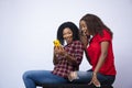 Shot of two beautiful black females looking surprised and feeling excited while looking at a phone Royalty Free Stock Photo