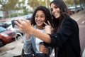 Two beautiful businesswomen making a video call with smart phone while drinking coffee walking around the city Royalty Free Stock Photo