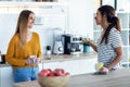 Two beautiful woman friends having breakfast and drinking coffee while talking in the kitchen at home Royalty Free Stock Photo