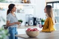 Two beautiful woman friends having breakfast and drinking coffee while talking in the kitchen at home Royalty Free Stock Photo