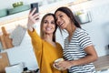 Two beautiful woman friends having breakfast and drinking coffee while talking in the kitchen at home Royalty Free Stock Photo