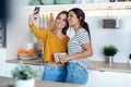 Two beautiful woman friends having breakfast and drinking coffee while talking in the kitchen at home Royalty Free Stock Photo