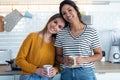 Two beautiful woman friends having breakfast and drinking coffee while talking in the kitchen at home Royalty Free Stock Photo