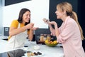 Two beautiful women tasting the healthy dishes they have prepared in the kitchen at home.