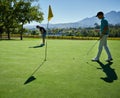 Putting the whole day. Shot of two focused young men playing a game of golf outside on a golf course. Royalty Free Stock Photo