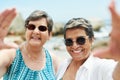 How can we not a selfie on the beach. Shot of two mature friends standing together and posing for a selfie during a day Royalty Free Stock Photo