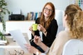 Two pretty young business woman relaxing one moment while drinking coffee in the office. Royalty Free Stock Photo