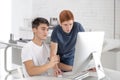 Two serious teenager guys are using computer and discussing something