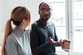 Two young business people talking and drinking coffee while taking a break in the office Royalty Free Stock Photo