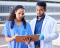 Fading optimism. Shot of two young doctors checking some paperwork while outside in the city. Royalty Free Stock Photo