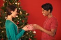 A gift for my bestie. Shot of two young women exchanging gifts at Christmas. Royalty Free Stock Photo