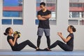 Working out is better with a friend. Shot of two young women exercising with a trainer at the gym.