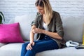 Uncomfortable young woman scratching her arm while sitting on the sofa at home Royalty Free Stock Photo