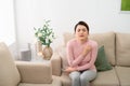 Shot of uncomfortable young woman scratching her arm while sitting on the sofa at home Royalty Free Stock Photo