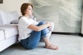 Portrait of unhappy lonely and depressed young woman hiding her face between legs at home Royalty Free Stock Photo