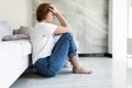 Portrait of unhappy lonely and depressed young woman hiding her face between legs at home Royalty Free Stock Photo