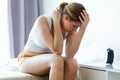 Unhappy lonely depressed young woman sitting on bed at home. Depression concept.