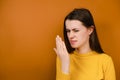 Shot of unhappy young woman checking her breath with hand, smells something awful, pinches nose, frowns in displeasure Royalty Free Stock Photo