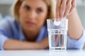 Unhealthy young woman looking at a glass with an effervescent pill at home.