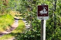 A shot up trail sign with a road in the distance Royalty Free Stock Photo