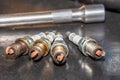 Shot of used spark plugs on a table with socket wrench blurred in the background Royalty Free Stock Photo