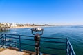 A shot of the vast blue ocean water and beach from the pier with a telescope and blue railing on the pier with blue sky Royalty Free Stock Photo