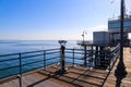 A shot of the vast blue ocean water and beach from the pier with a telescope and blue railing on the pier with blue sky Royalty Free Stock Photo