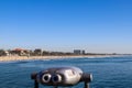 A shot of the vast blue ocean water and beach from the pier with a telescope and blue railing on the pier with blue sky Royalty Free Stock Photo