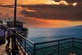 A shot of the vast blue ocean water at the pier with large breaking waves at sunset with powerful red clouds at sunset Royalty Free Stock Photo