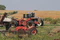 A shot of a Versatile farm tractor and Kubota tractor in a farm field with a fence and blue sky.