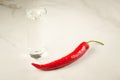 shot of vodka and red hot chili pepper on the bar/shot of vodka and red hot chili pepper on a white marble background. Selective Royalty Free Stock Photo