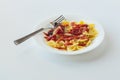 Shot on a white background. No isolation. White plate in it pasta and a piece of meat and a fork