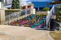 A shot of a white building with a colorful staircase, a waterfall, and a smooth stone footpath with blue sky at Little Sugar Creek