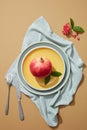 Shot of white plates of whole and sliced pomegranates, leaves and linen napkins on blue table